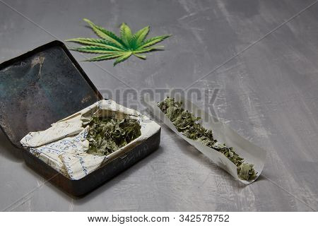 Cannabis Rolls On Its Own. Iron Can With Grass. Hemp On A Gray Beten Background