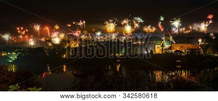 New Year Fireworks Above The Old Town Of Ratzeburg At Night With Illuminated Cathedral And Reflectio