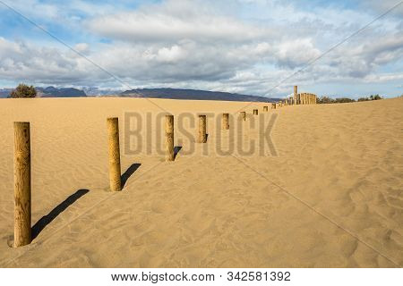 Sand In The Dunes Of Maspalomas, A Small Desert On Gran Canaria. Sand And Sky, And A Wooden Fence Ma
