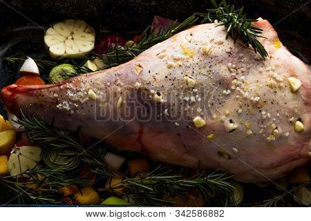 Raw Leg Of Lamb Dressed With Vegetables.