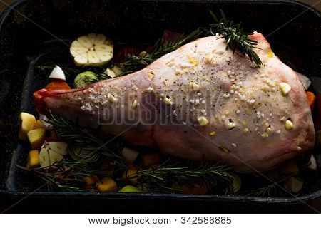 Raw Leg Of Lamb Dressed With Vegetables.