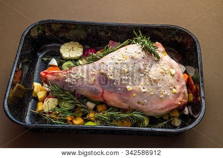 Raw Leg Of Lamb In Roasting Tray Dressed With Vegetables.
