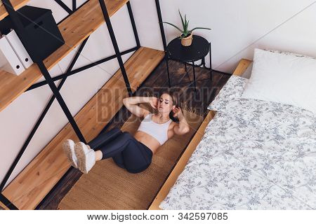 Attrctive Fitness Woman Doing Stretching Exercises At Home, As Part Of A Healthy Lifestyle Without G