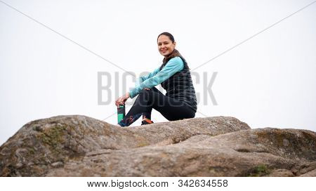 Beautiful Smiling Woman Resting and Drinking Water after Trail Running Outdoor. Workout Exercise at Cold Autumn Evening. Sport and Healthy Active Lifesyle Concept.
