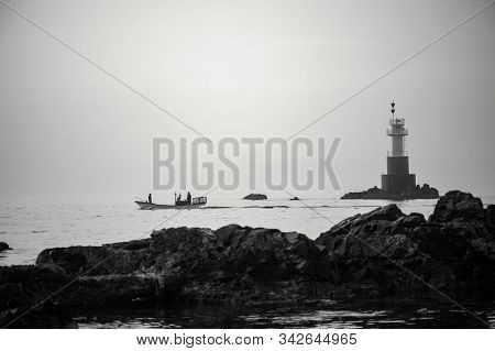A Fishing Boat Leaving Fishing In The Early Morning Past The Lighthouse