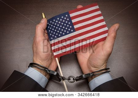 The Hands Of A Businessman In Handcuffs Holding An American Flag 1
