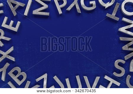 Frame Mockup Made Of Of Silver Metal English Alphabet Characters On Blue Background.