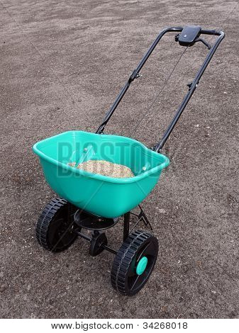 Seminatrice riempito con semi di erba girato sul suolo ad azionamento manuale