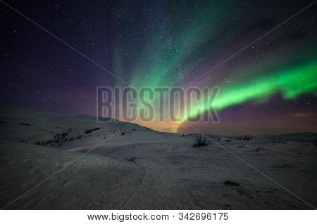 Northern Lights, Polar Lights With Many Clouds And Stars On The Sky Over Mountains In The North Of E