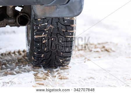 An Unadorned Picture Of Winter Car Wheel With Metal Spikes On Snow Close-up