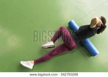 Woman Doing Foam Roller Exercise On A Floor In Gym