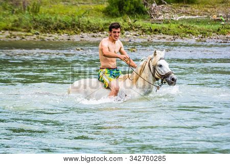 Draj-rec, Albania - July 27, 2014. Young Albanian Boy Riding On The White Horse In Black Drin River 