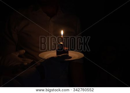 Birthday Cake With A Single Candle Being Presented By A Waiter Or Server