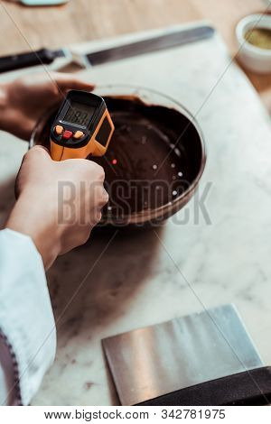 Cropped View Of Chocolatier Holding Cooking Thermometer Near Bowl With Melted Dark Chocolate