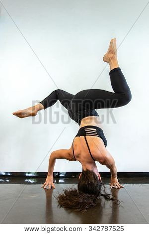 A Woman Is Seen Upside Down From Behind As She Performs A Twisting Splits In Headstand Posture Durin