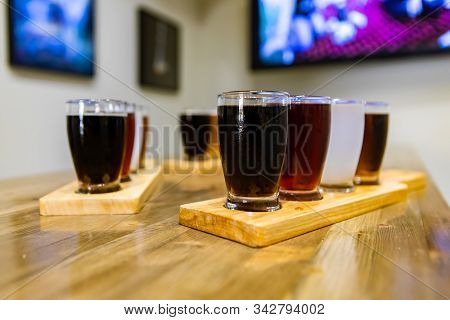 Flight Of Craft Four Of Different Beers Glasses On Wooden Trays During A Tasting Session, Selective 
