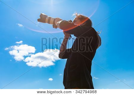 Young Male Photographer With Telephoto Lens Attached To Dslr Camera Shooting Leftwards Towards The S