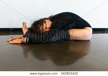 A Healthy Woman In Dark Gym Clothes And Leg Warmers Is Seen With Symmetrical Reflection, Holding An 
