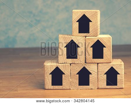 Pyramid Of Wooden Blocks With Upswing Arrows, Growth Or Aim High Concept