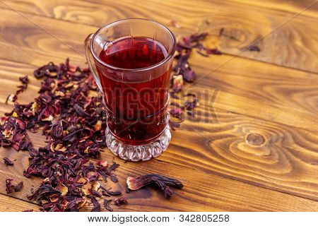 Glass Cup Of Red Hibiscus Tea (carcade, Roselle) On Wooden Table