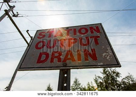 Low Angle View Of A White And Red Sign Against The Sky, Electric Towers And Cables, Station, Output,