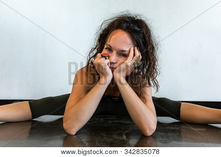 A Tired And Fed Up Looking Woman Is Seen From The Front, With Unkempt Brunette Hair In A Seated Yoga