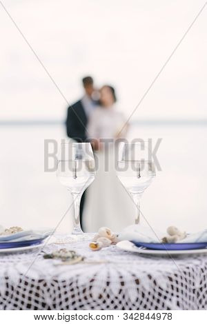 Two Glasses On The Background Of A Loving Couple Of The Bride And Groom Blurr