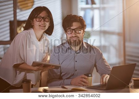 Portrait Of Young Business People Smiling At Camera While Working With Computer And Tablet Pc Till L