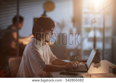 Asian Young Manager Sitting At The Table And Typing On Laptop Computer She Working Till Late Evening