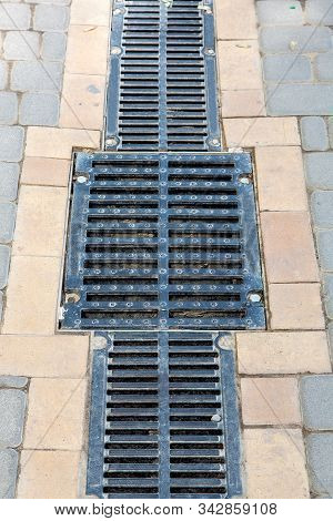 A Lattice Of A Drainage Paving System With Hatch Grill On A Walkpath Made Of Stone Tiles, Close Up.