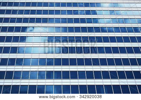 Geometric Reflection: Partly Cloudy Sky Reflected By Window Panes Of Office Building. Surface Of Gla