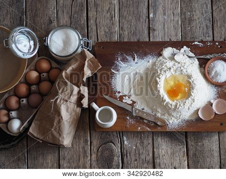Egg In Flour On A Cutting Board For The Preparation Of Dough With Ingredients On A Wooden Background