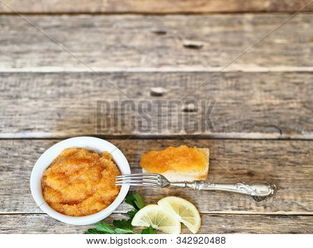 Pike Caviar In A White Plate. Near A Sandwich Of Bread With Caviar And Lemon On A Wooden Ancient Bac