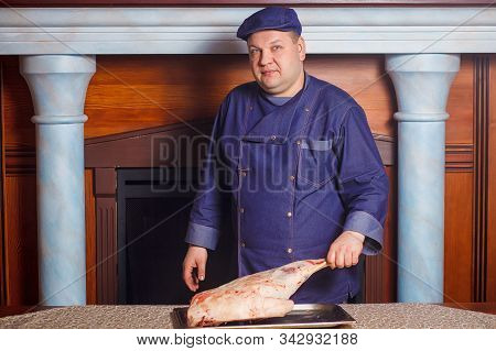 Half Legth Shot Of Thoughtful Male Chef, Holds Very Big Red Raw Piece Of Meat, Needs To Chop For Pre