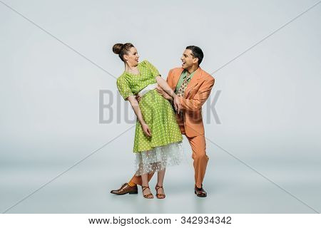 Cheerful Dancers Looking At Camera While Dancing Boogie-woogie On Grey Background