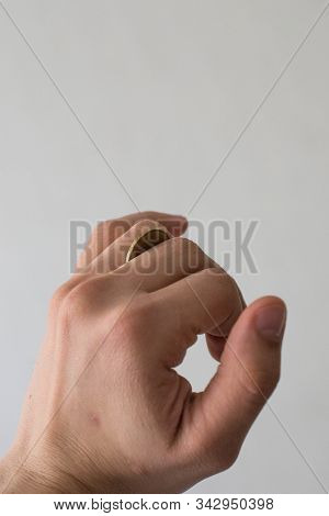Coin In Male Hand On Wall Background