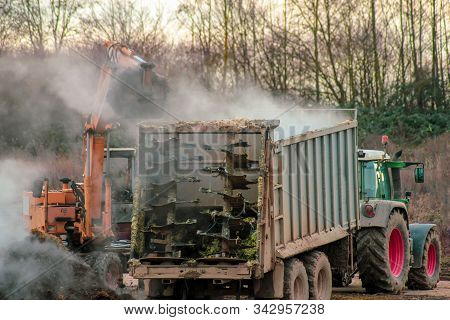 Excavator Loads Manure, Hovering In The Cold Air, Into A Tractor With A Trailer. Late Fall. Animal H