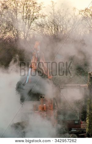 Excavator Loads Manure, Hovering In The Cold Air, Into A Tractor With A Trailer. Late Fall. Animal H