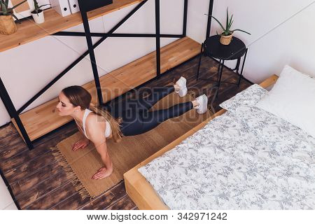 Attrctive Fitness Woman Doing Stretching Exercises At Home, As Part Of A Healthy Lifestyle Without G