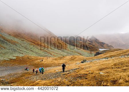 Tourists Travelers With Backpacks Climb The Rocks In Dense Fog. Poor Visibility And Easy To Get Lost