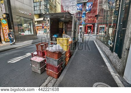 Tokyo, Japan - Circa 2018: Goods delivery truck stopped on a downtown street to unload supplies for restocking a city shop, busy japanese urban area