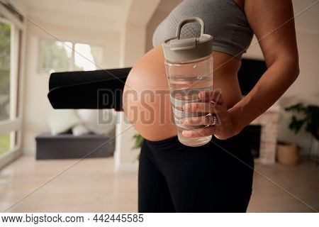 Caucasian Female Woman Standing In Living Room With Water Bottle And Yoga Mat