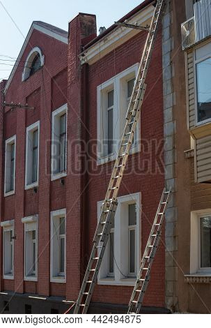 An Extension Ladder Leans Against The Front Of A Multifamily Housing Building In Preparation Of Roof