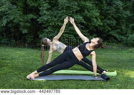 Two Slender Girls Do Yoga In Park. Side Plank. Vasishthasana. Healthy Lifestyle. Sports Activities I