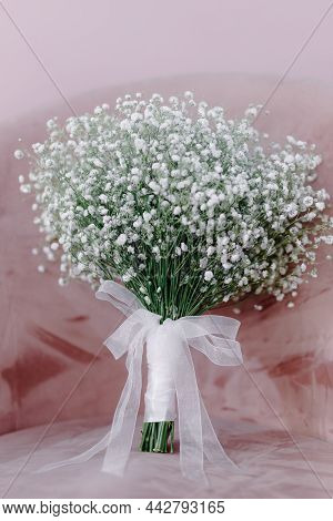 Bridal Bouquet Of Flowers With White Ribbon Stands On A Pink Chair