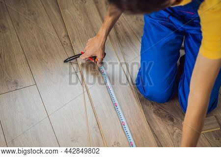 Man Installing New Wooden Laminate Flooring On A Warm Film Floor. Infrared Floor Heating System Unde
