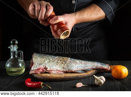 The Chef Prepares Fresh Fish Sprinkling Pepper. Preparing To Cook Fish Food. Working Environment In 