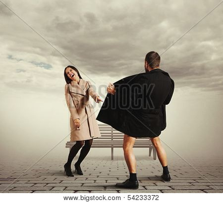 laughing woman pointing at exhibitionist in the street