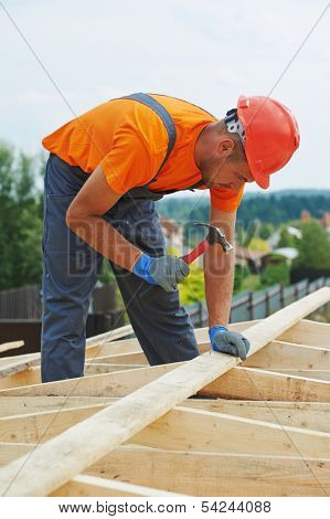 construction carpenter worker nailing wood board with hammer on roof installation work