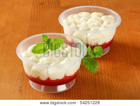 two plastic cups with yogurt dessert, on a table